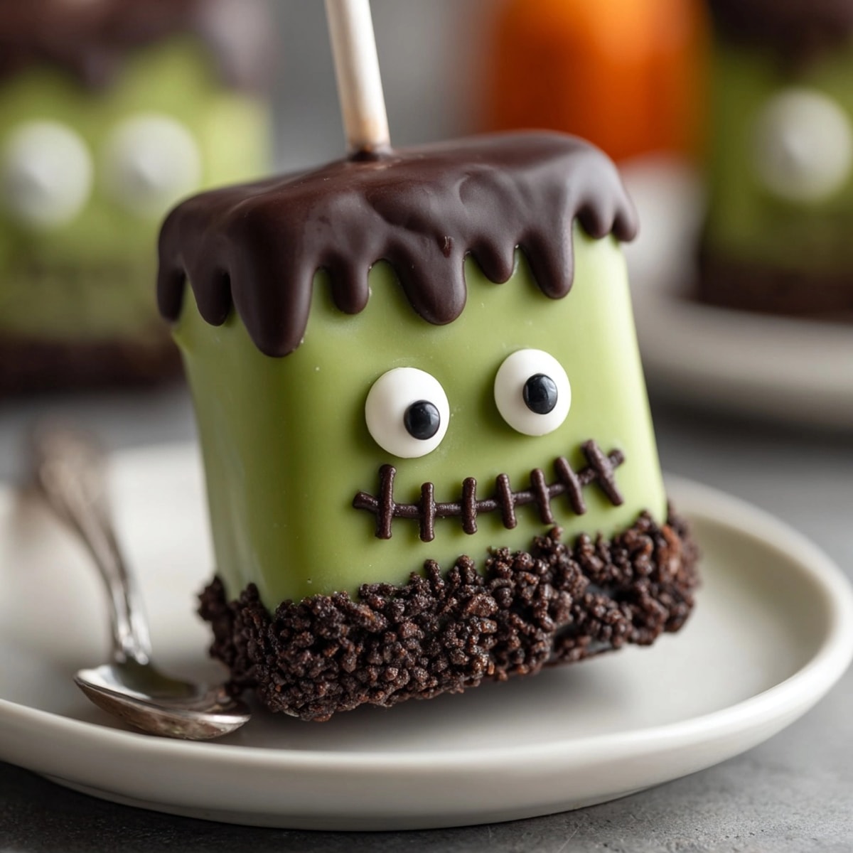 Close-up of gooey green Frankenstein Marshmallow Pops, chocolate hair, candy eyes, Halloween dessert.