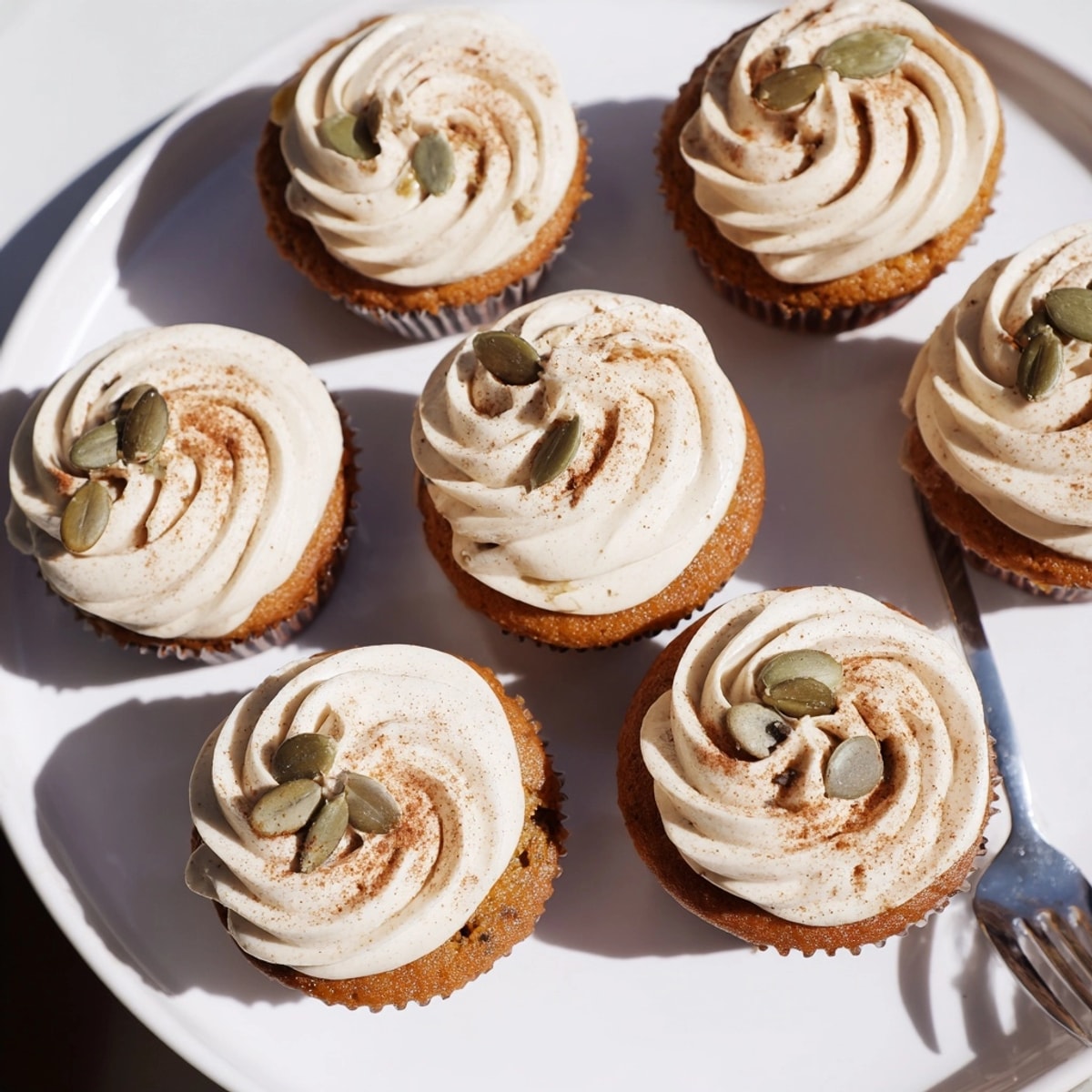 Close-up Vanilla Chai Pumpkin Latte Cupcakes: frosted swirls dusted with spice, autumn dessert.