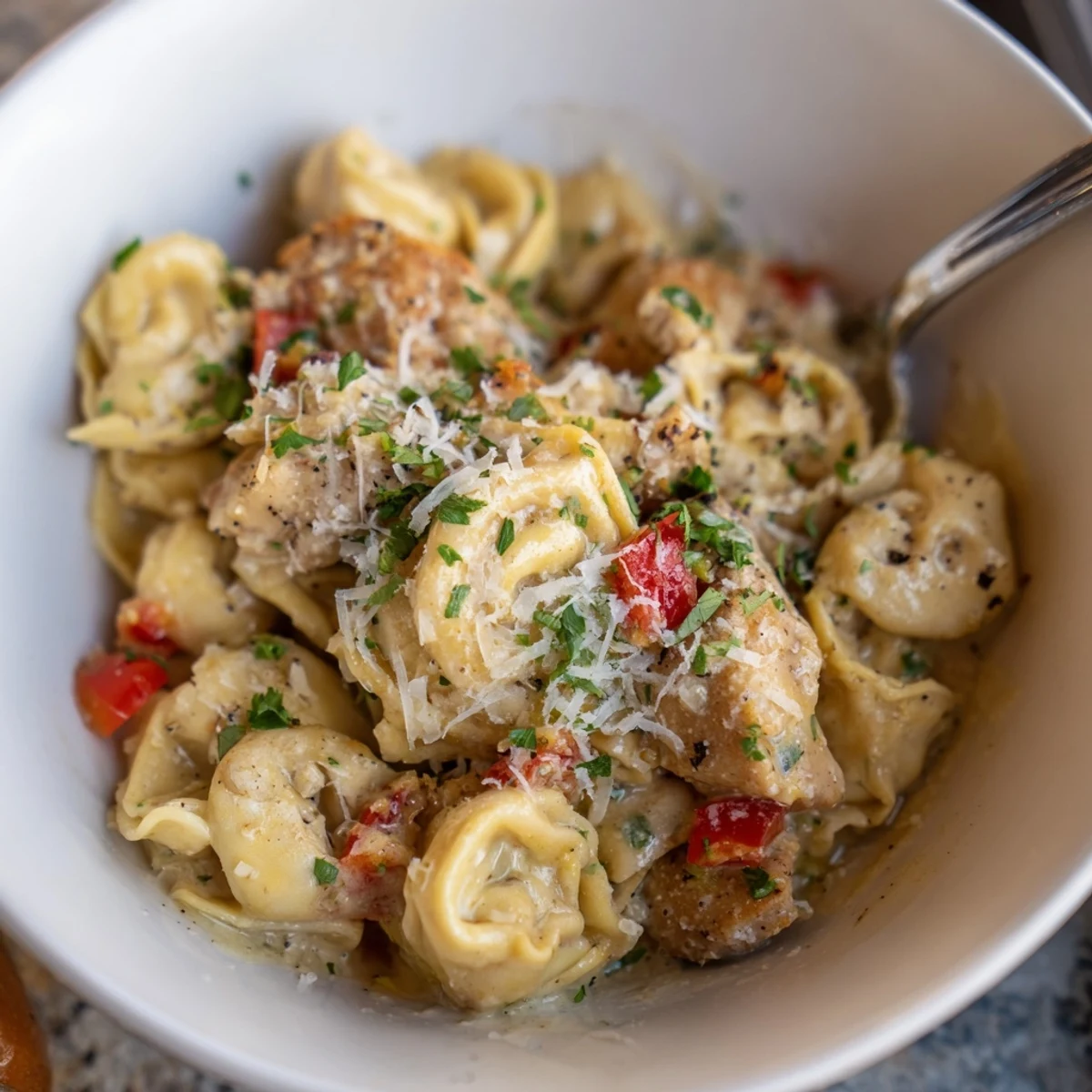 Zesty Cajun Garlic Parmesan Chicken Tortellini served with fresh parsley and extra cheese.  