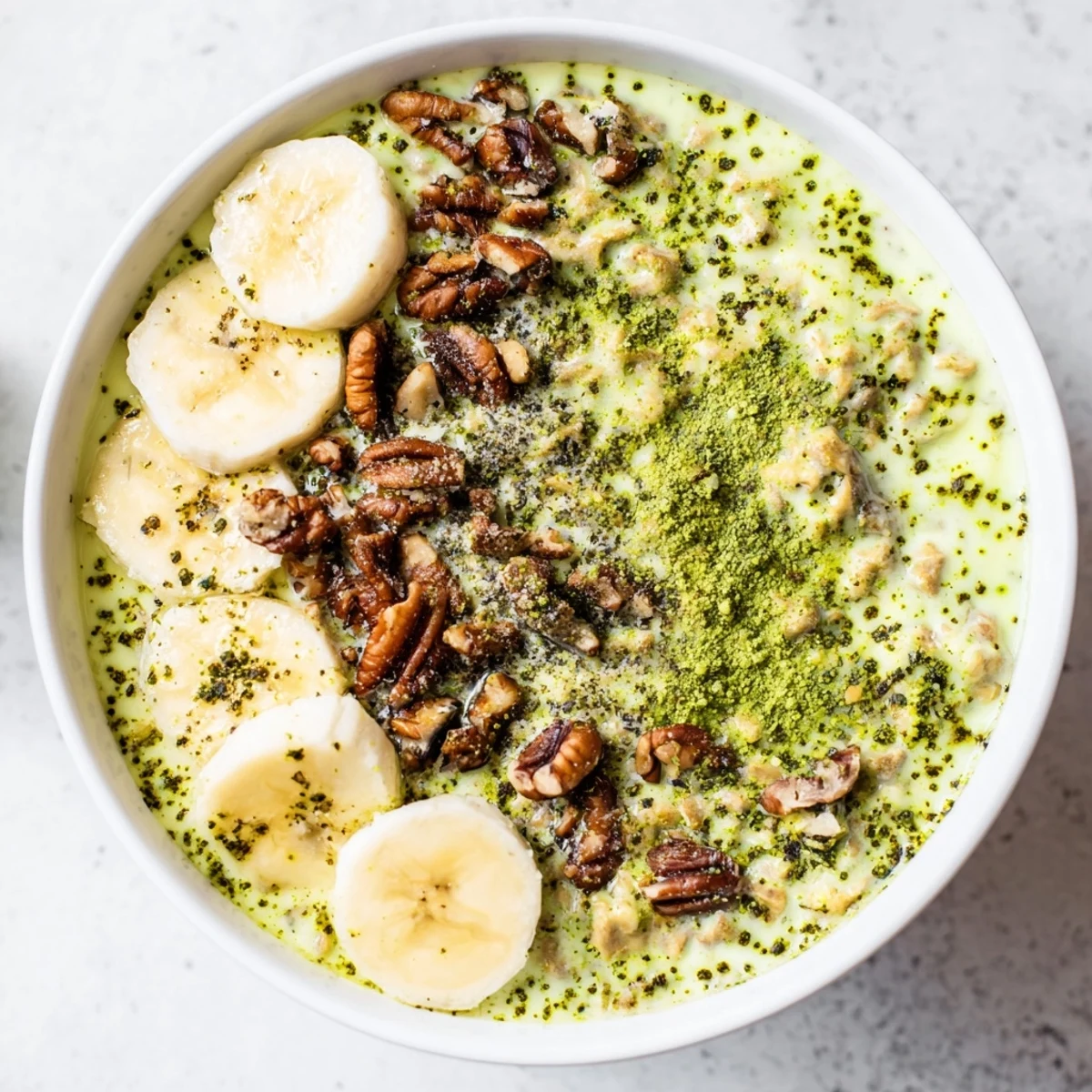 A layered jar of High-Protein Eggnog Matcha Overnight Oats, chilled and topped with pecans and cinnamon.