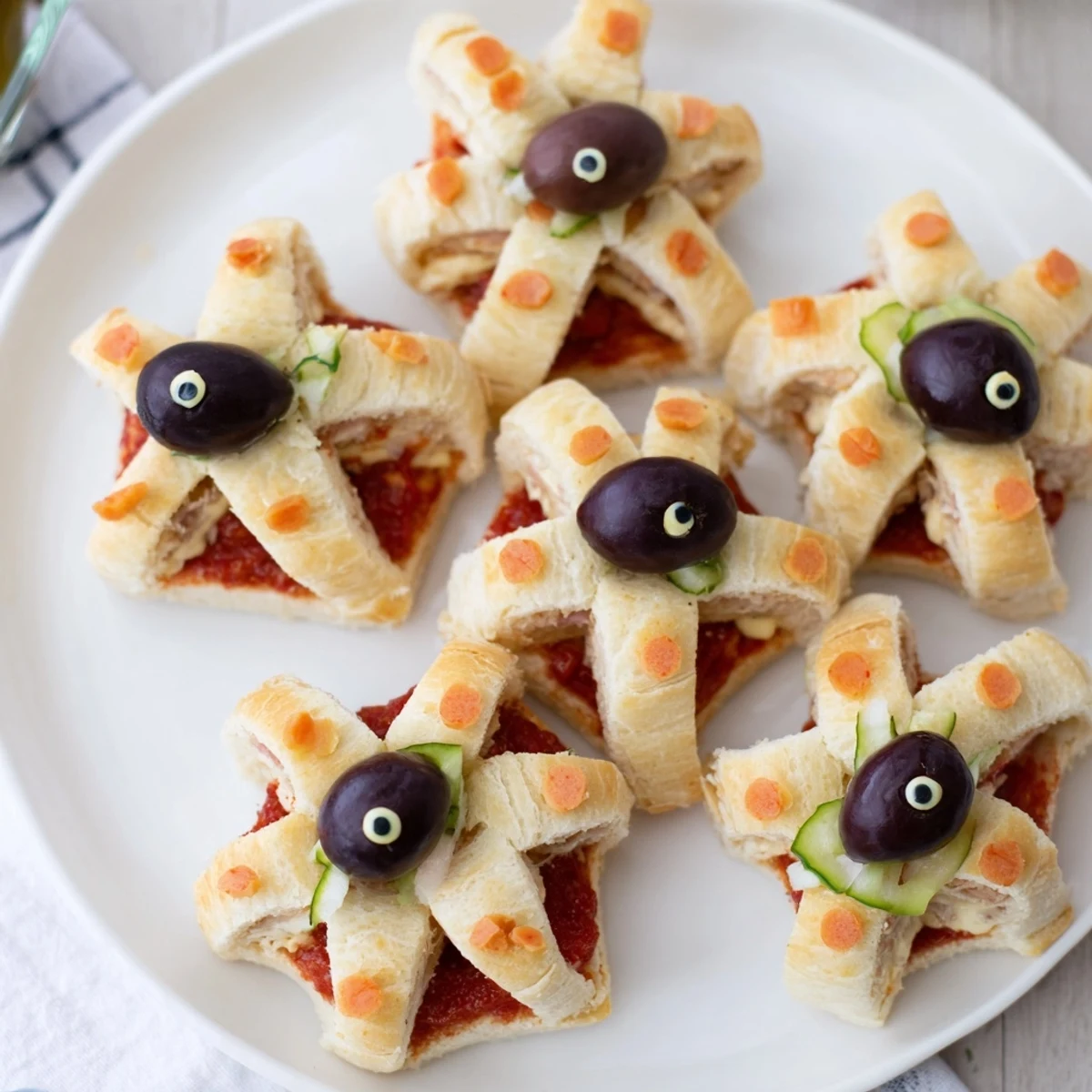 Freshly assembled Mini Starfish Sandwiches displaying tuna filling, olives, and capers, perfect for a party.