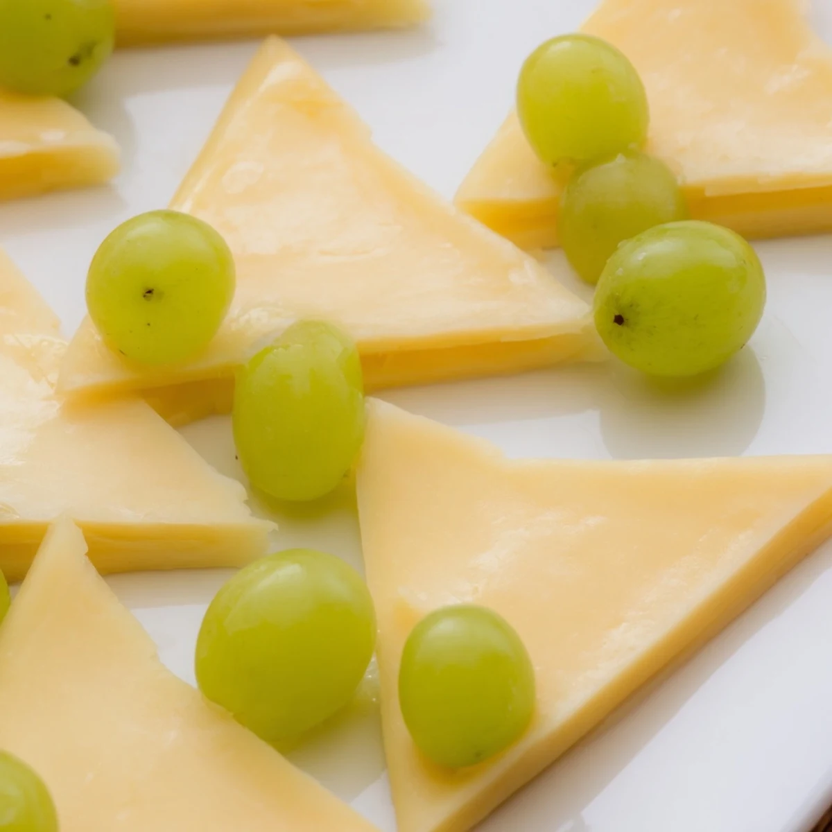 Festive The Tannenbaum Border cheese board with green grape "trees," perfect for holiday entertaining.