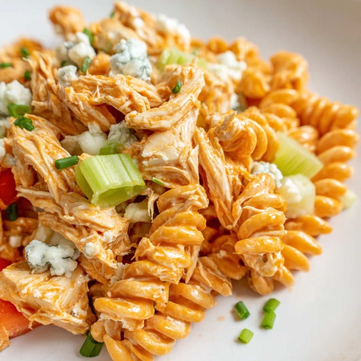 A chilled bowl of Buffalo Chicken Pasta Salad, featuring rotini pasta, shredded buffalo chicken, celery, red bell peppers, and creamy ranch dressing.