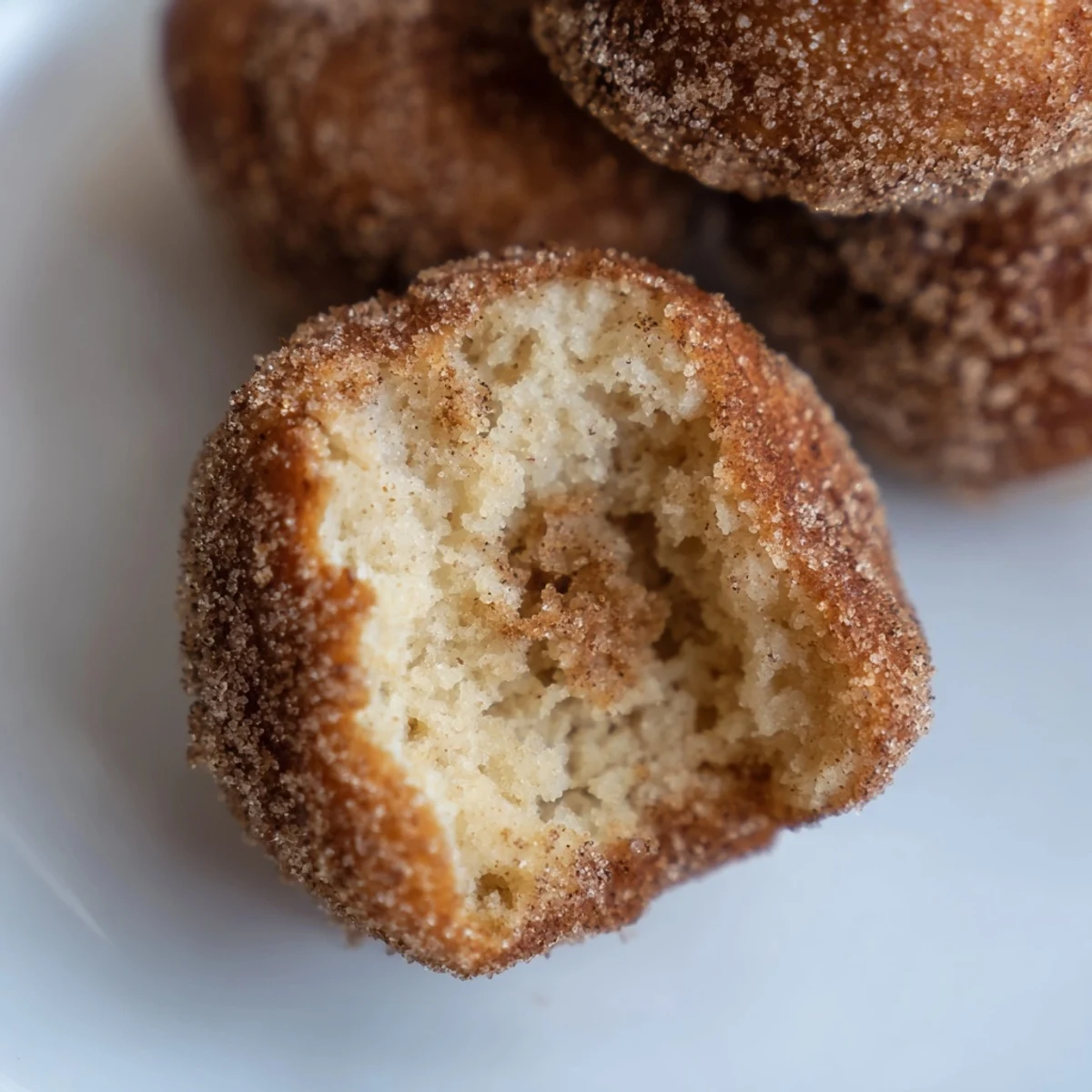 Golden brown air fryer cinnamon donuts, freshly coated in sweet cinnamon sugar, ready to eat.