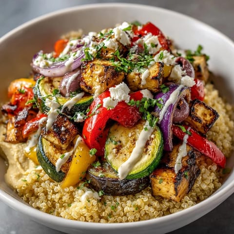 Fresh Mediterranean Quinoa Power Bowl topped with lemon-herb tahini dressing, cucumber, and juicy tomatoes.