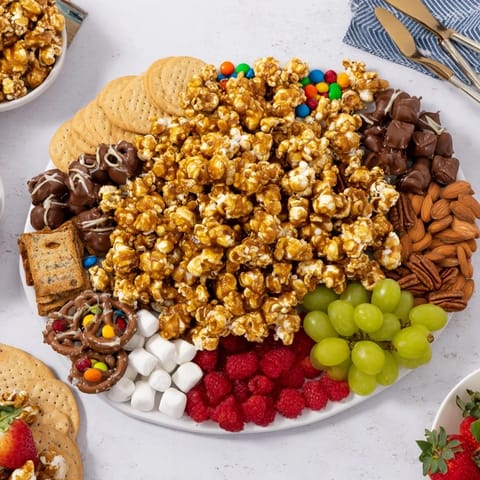 Enticing caramel popcorn charcuterie board, complete with sweet treats and crunchy nuts.  
