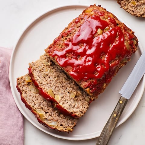 Juicy, flavorful slices of Effortless Stove Top Stuffing Meatloaf served alongside creamy mashed potatoes.