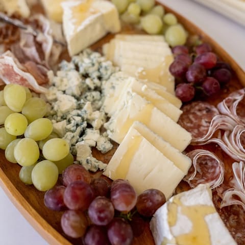 A carefully arranged Elegant Gilded Edge appetizer board, featuring ripe grapes and artisanal cheeses for guests.