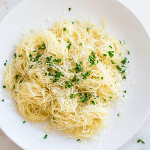 Lemon Capellini glistens with lemon butter sauce, garnished with fresh herbs, ready for a delicious dinner.