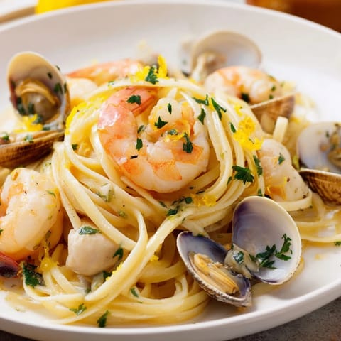 Golden seafood linguine served with fresh parsley and lemon wedges, ready for a delicious Italian meal.