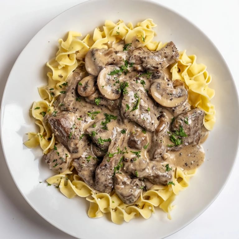 Enjoy a comforting bowl of Creamy Mushroom Beef Stroganoff: beautifully plated, complete with a garnish of fresh parsley.