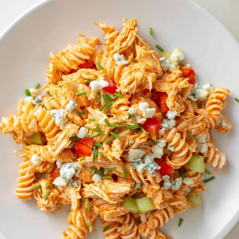 Cold pasta salad with spicy buffalo chicken, crunchy vegetables, and ranch dressing, perfect for a summer potluck or picnic side dish.