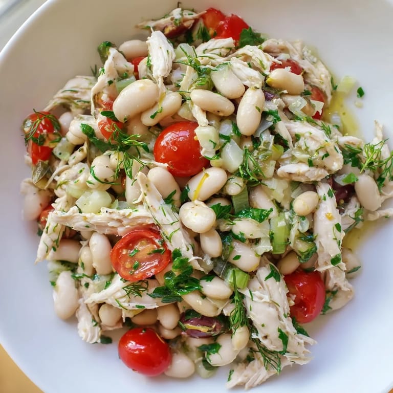 Freshly tossed Lemony White Bean Chicken Salad, mixing juicy chicken, white beans, and herbs with a tangy lemon dressing in a rustic bowl.
