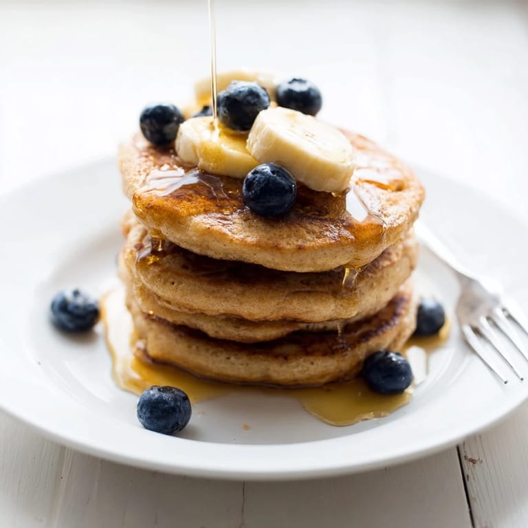 A fork lifts a bite of Protein Power Pancakes, revealing a tender, airy interior and a generous dollop of Greek yogurt.