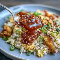 Chili Crisp Egg Fried Rice with fluffy eggs and chili oil, garnished with scallions and sesame seeds.